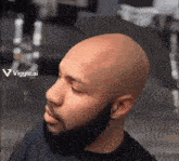 a man with a beard and a bald head is looking to his left