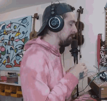 a man wearing headphones is singing into a microphone in front of a painting