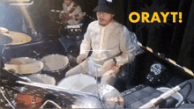 a man is playing drums in front of a sign that says orwyt