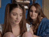 two women are sitting next to each other and one of them has pigtails