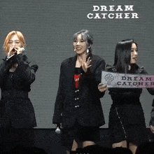 three women holding a sign that says " dream catcher "