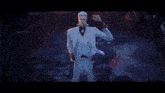 a man in a white suit is surrounded by people
