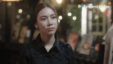 a woman in a black shirt stands in front of a tencent video sign