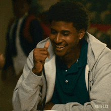 a man wearing a grey hoodie and a green shirt is smiling with a netflix logo in the corner