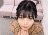 a young woman in a plaid shirt is making a face with her hands .