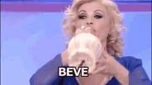 a woman in a blue dress is drinking from a cup and the word beve is on the bottom .