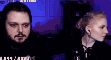 a man and a woman are sitting next to each other in front of a microphone in a dark room .