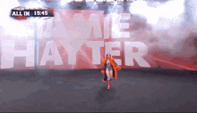 a woman in an orange coat is walking in front of a banner that says jamie hayter