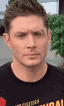 a man wearing a black shirt that says " no obsessed " on it