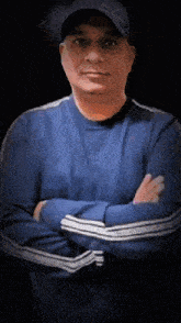 a man with his arms crossed is wearing a blue shirt and a black hat