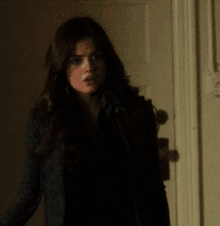 a woman in a black jacket stands in a doorway