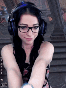 a woman wearing headphones and glasses with a tab button on the bottom right