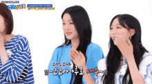 a group of girls are sitting next to each other and one of them is wearing a blue shirt that says secret number