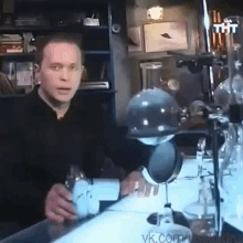 a man is sitting at a table in a lab holding a flask .