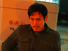 a man standing in front of a box that says fq on it