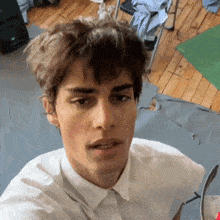 a young man wearing a white shirt and earrings looks at the camera