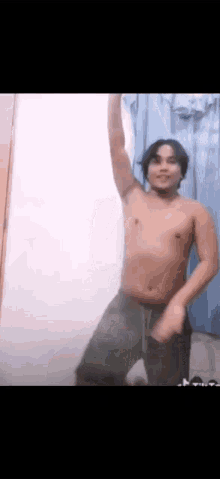 a shirtless man is dancing in a room with his arm in the air .