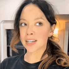 a close up of a woman 's face with a ponytail and a black shirt