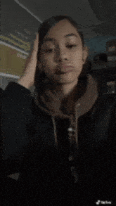 a girl in a black jacket is taking a selfie in a dark room .