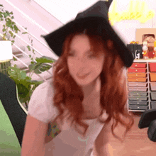 a woman with red hair is wearing a witch hat .