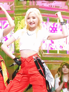 a blonde woman in a white crop top and red pants is dancing