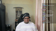 a man wearing a hat and glasses is sitting in front of a screen with a bunch of letters on it