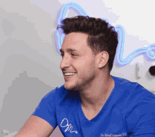 a smiling man wearing a blue shirt that says dr. mihail yurhaski d.o.