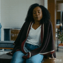 a woman is wrapped in a blanket while sitting on a couch .