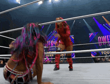 two women are wrestling in a ring with the word owen on the wall