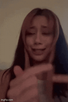a close up of a woman holding her finger to her mouth .
