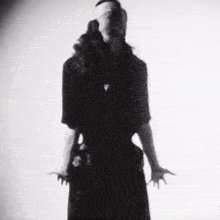 a black and white photo of a woman in a black dress with her eyes closed .