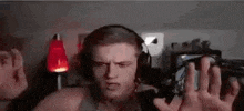 a man wearing headphones is standing in front of a microphone in a dark room .