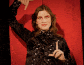 a woman in a black shirt is making a hand gesture with her fingers