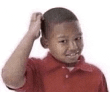 a young boy is scratching his head while wearing a red shirt .