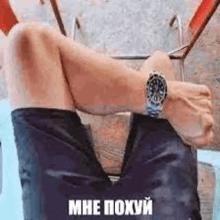a man wearing a watch is sitting on a chair with his legs crossed and his feet up .