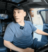 a man wearing a hat and a blue shirt is sitting in a car