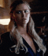 a woman with blonde hair is wearing a blue dress and earrings .