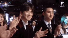 a man in a suit and tie applauds at a music awards