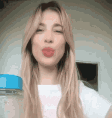 a woman blowing a kiss while wearing a white shirt with the word love on it