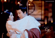 a man is carrying a woman in his arms in a traditional costume .