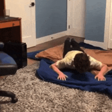a man is laying on a blue blanket on the floor .