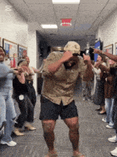 a group of people are dancing in a hallway with the exit sign above them