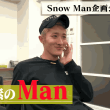 a man wearing a black hat and a black sweater with snow man written on it
