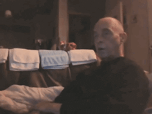 a man in a black shirt is sitting in front of a row of blue towels