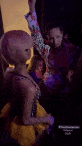 a woman in a yellow feathered skirt is dancing with another woman in a blue dress