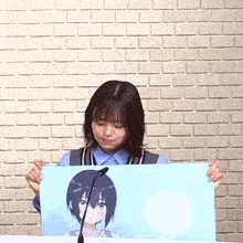 a woman holding a picture of a girl with short hair in front of a brick wall