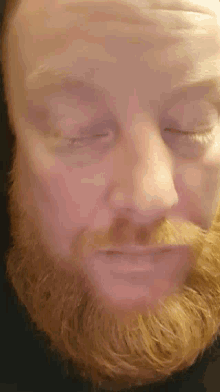 a man with red hair has his eyes closed