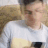 a blurry picture of a man sitting in a chair looking at his cell phone