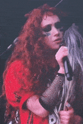 a woman with red hair is singing into a microphone while another woman with blonde hair is looking at her .