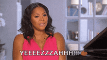 a woman in a pink dress is sitting in front of a piano and saying yeeeezzahh !!!